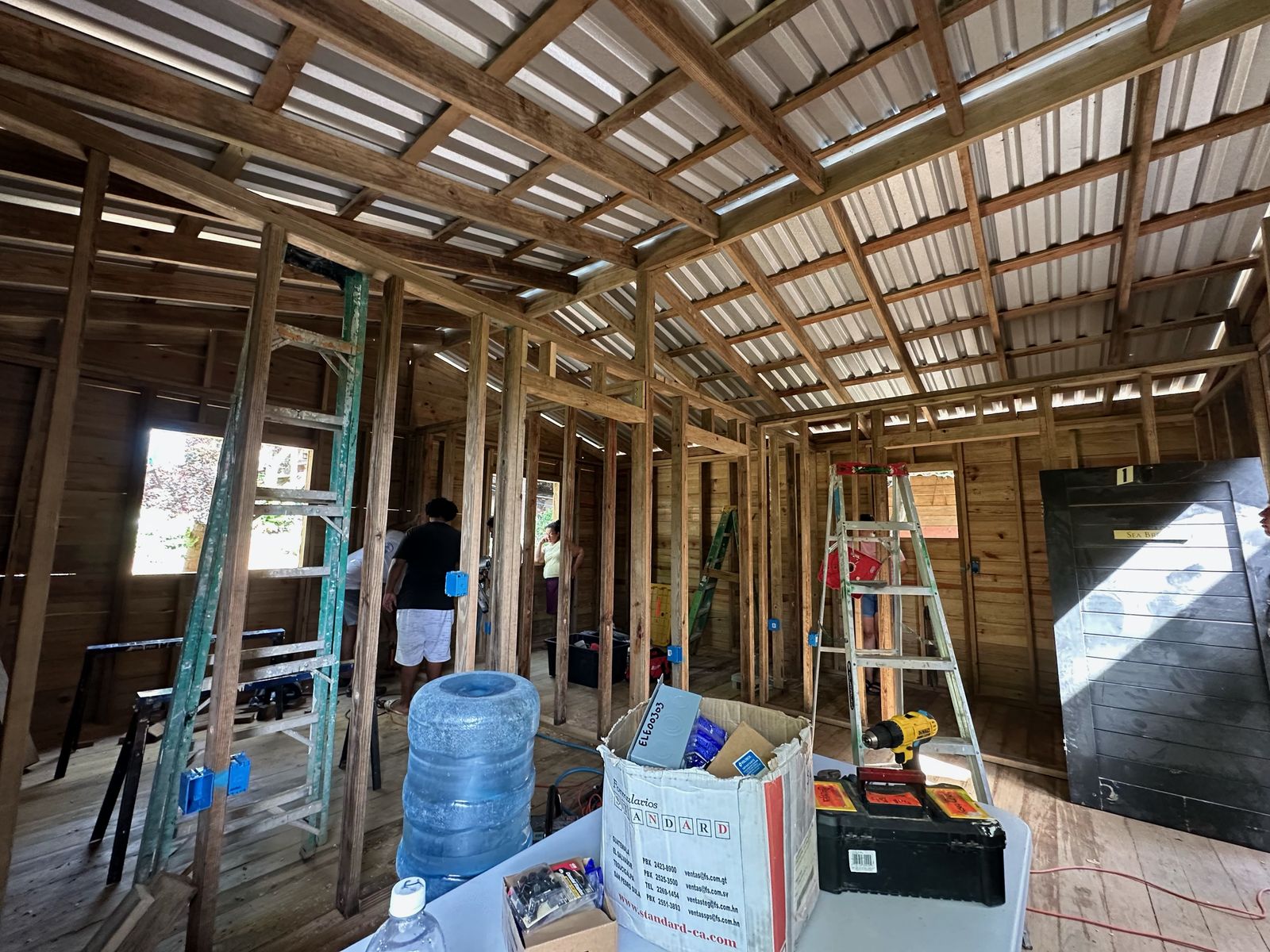 Framed interior walls for the bedrooms and bathroom under the new roof, with a dark door leaning ready to hang